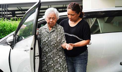 Caregiver help Asian elderly woman disability patient get in her car, medical concept.